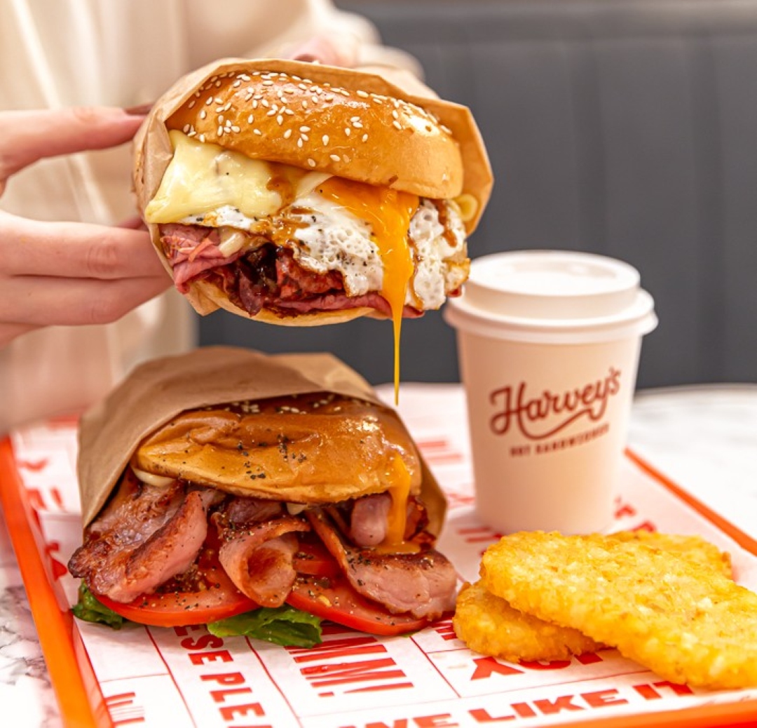 Image of two breakfast sandwiches, with a coffee and two hash browns