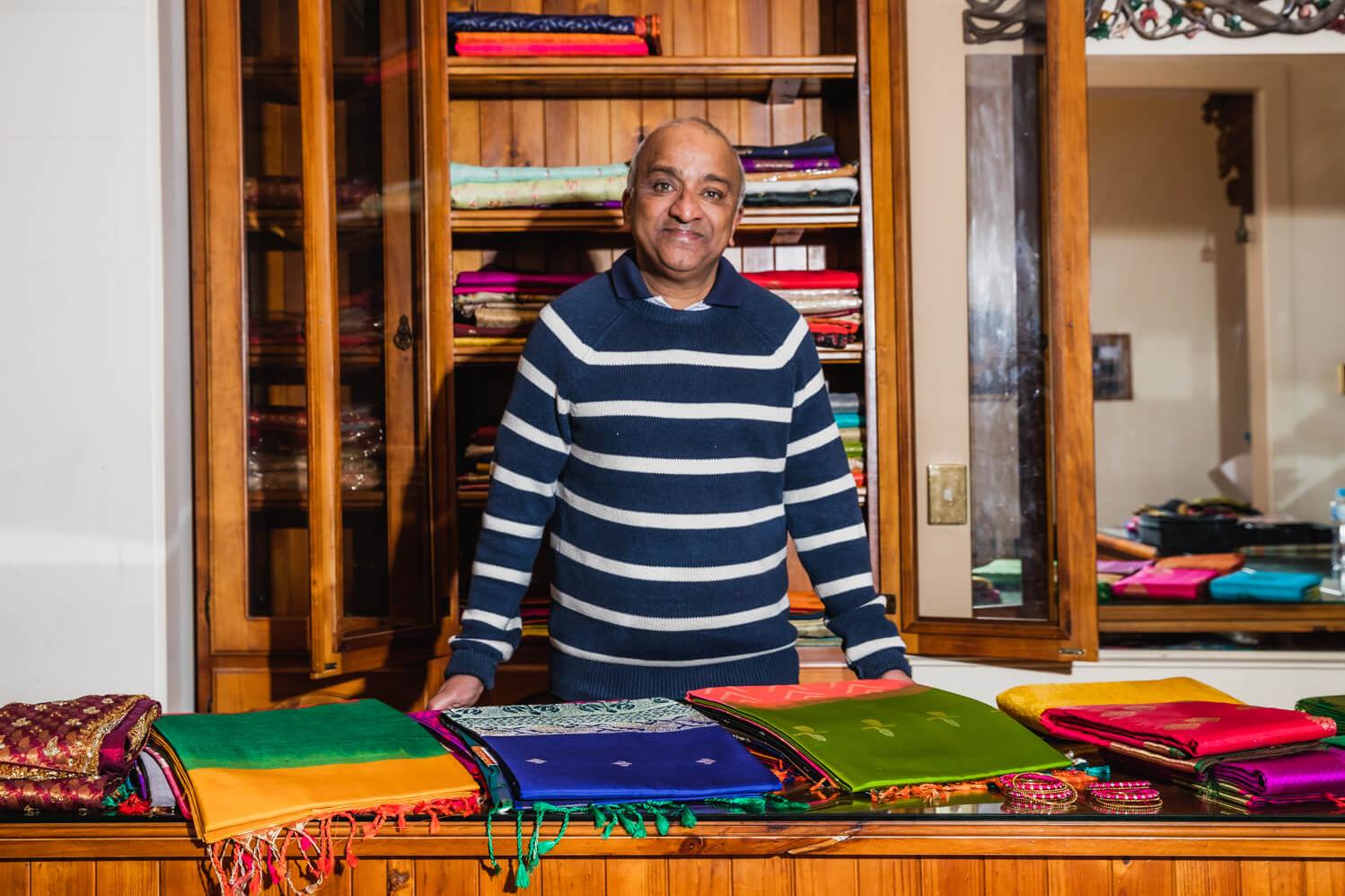 Saree Shop Owner standing in front of fabric